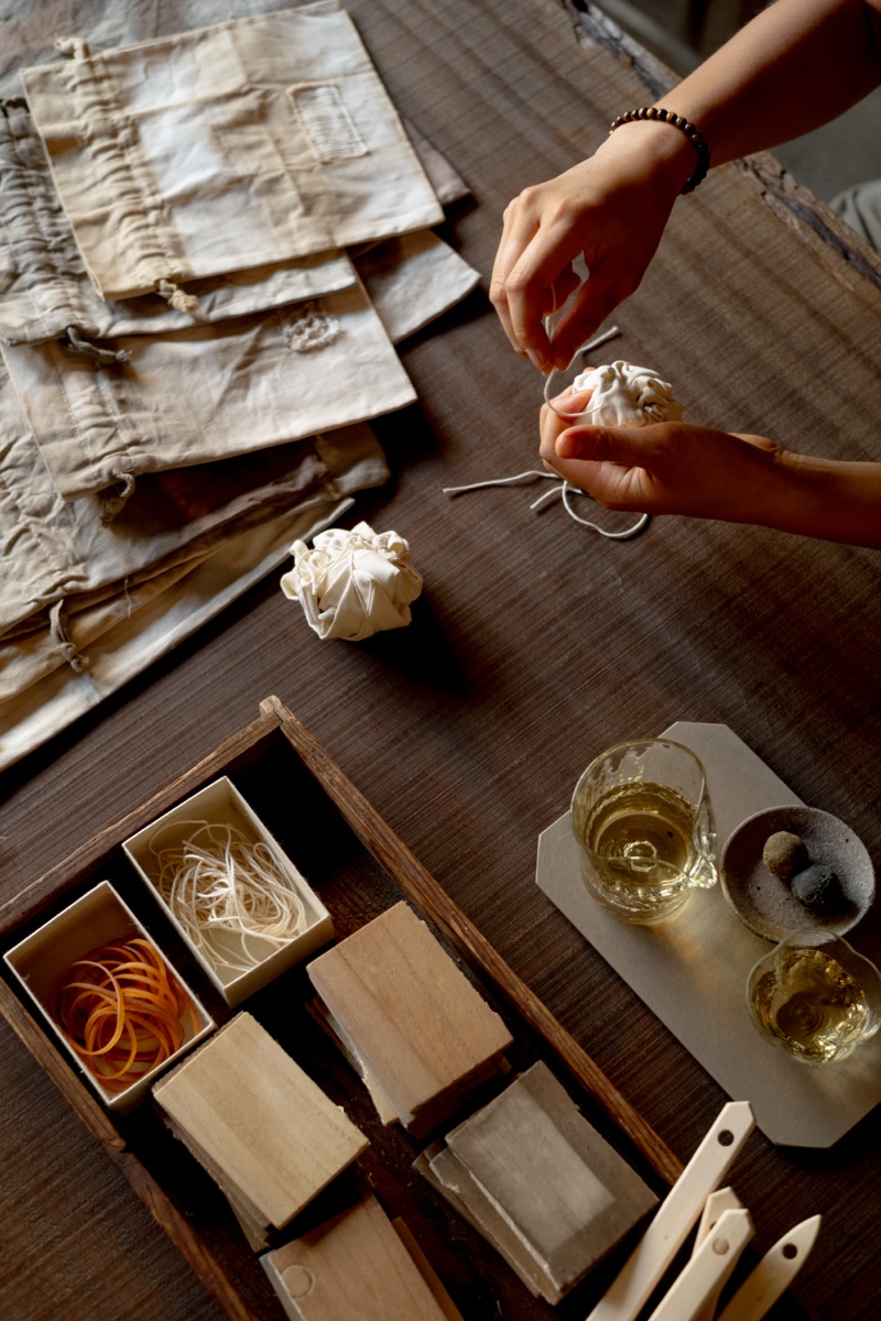 Hands tying a cotton bag in preparation for tea dyeing